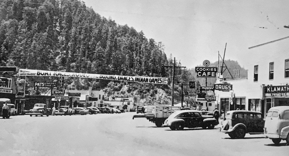 Cars, buildings, and a banner with forested hillside in background