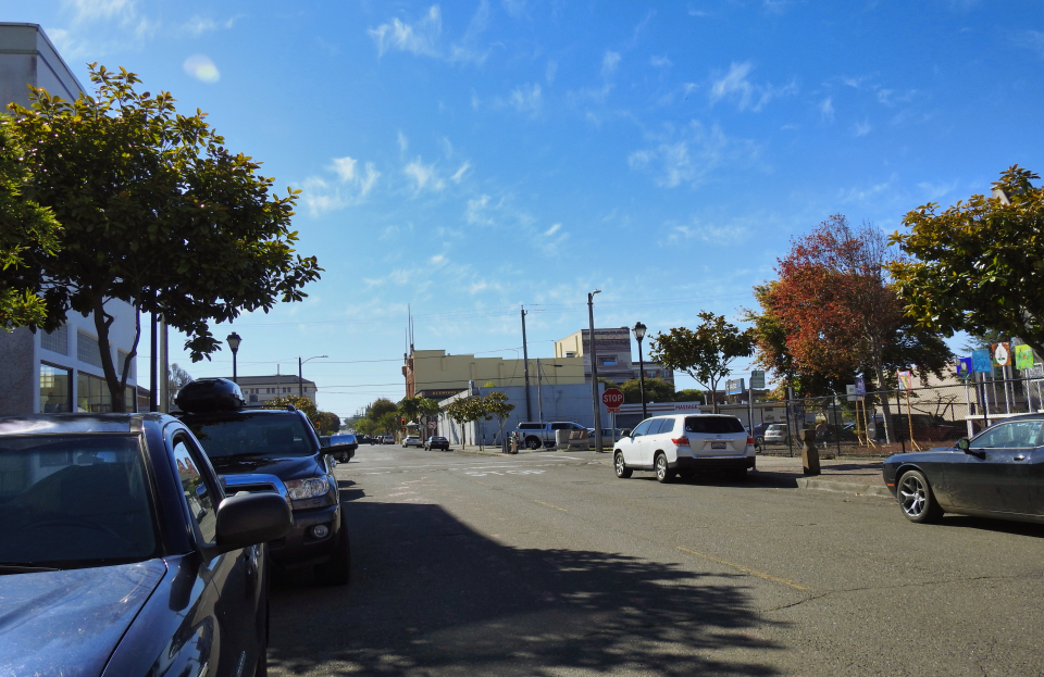 Church with steeple, dirt road, buildings and forest.