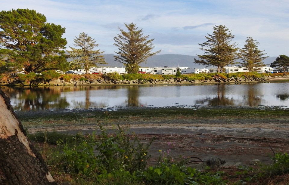 Ocean bay and beach with mountains in background, buildings in foreground.