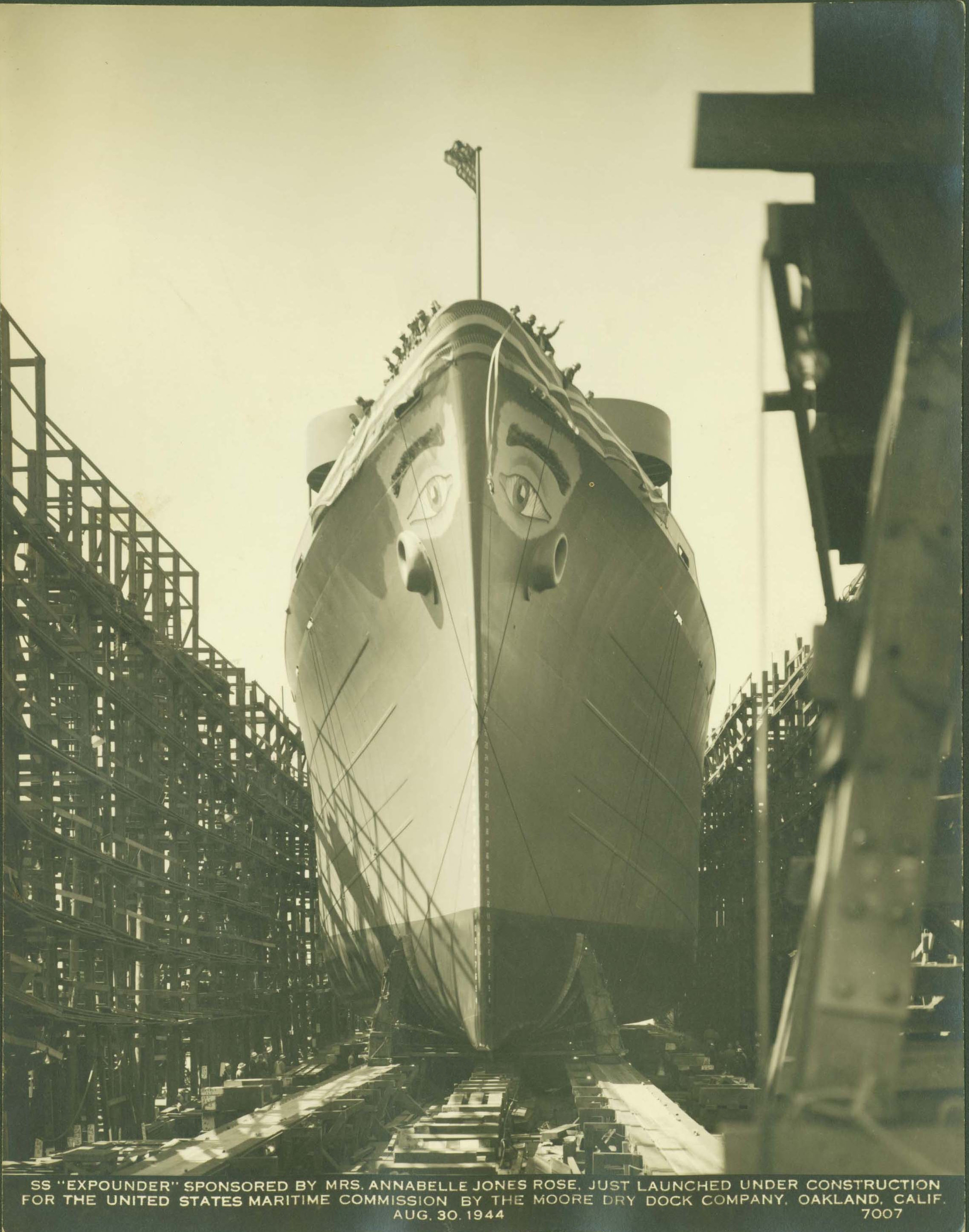 A ship sits in a launch berth. It has eyes painted on the top of both sides.