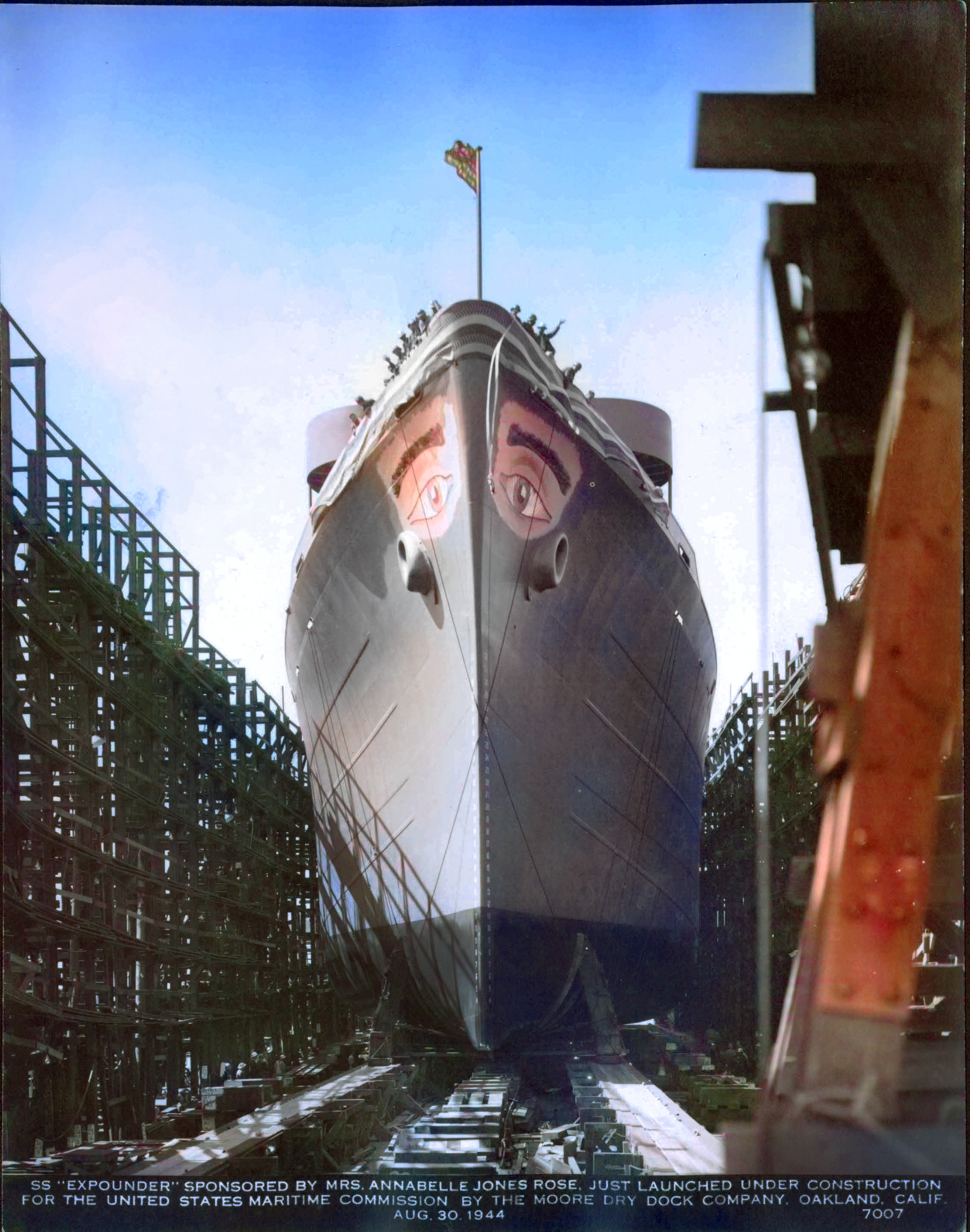 A ship sits in a launch berth. It has eyes painted on the top of both sides.
