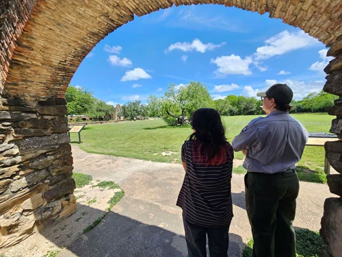 Photo of park ranger on the grounds of Mission Espada, with guest
