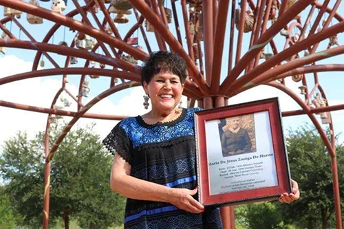 Woman holding a photo panel of her family member with text below