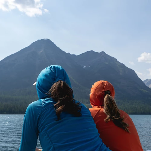 Two people look at a mountain over a lake