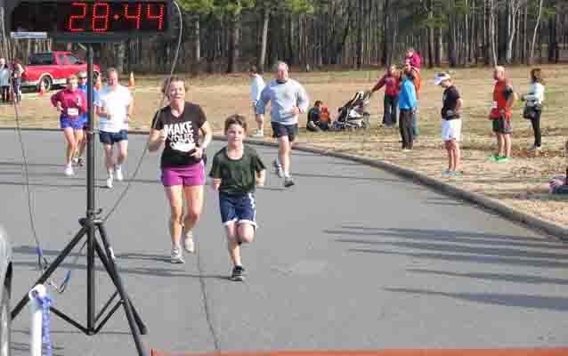 Families cross the finish line together at the Race for the Grasshopper