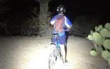 A child on a moonlit bike ride through Saguaro National Park.