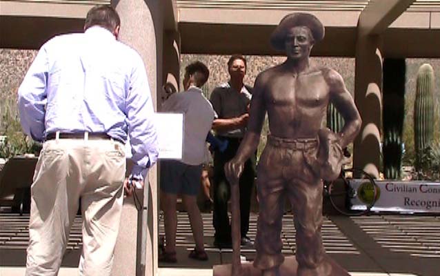 visitor is reading a sign explaining the history of “The CCC Worker statue” that is placed in more than 50 localities throughout the U.S.