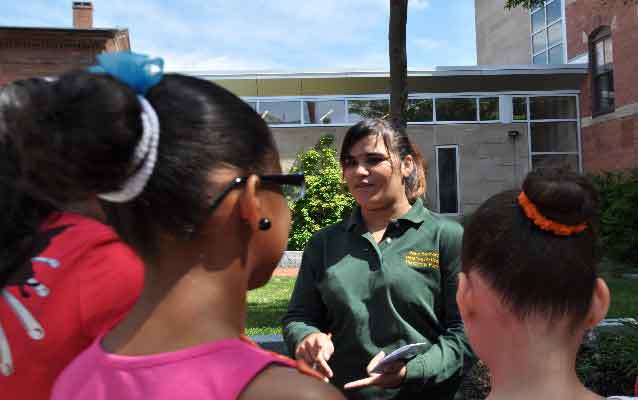 Learner to Teacher Arelys, wearing her NPS volunteer polo talks with elementary age English language learners.