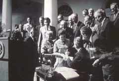 black and white photo of numerous people around a table