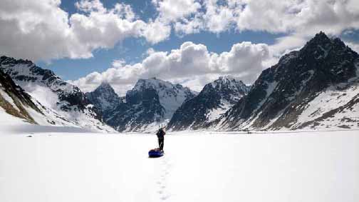 a person skiing across a vast glacier with snowy mountains in the distance a person skiing across a vast glacier with snowy mountains in the distance