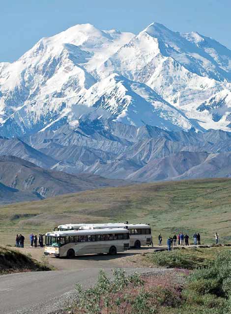 people standing near buses, looking at a vast snowy mountain people standing near buses, looking at a vast snowy mountain