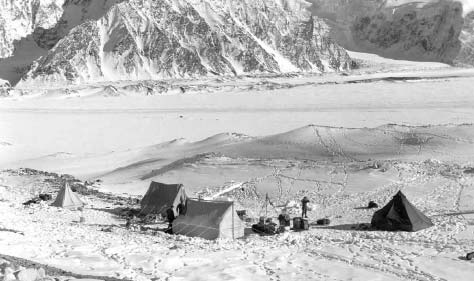 several tents in a snowy plain surrounded by mountains