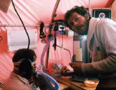 a man tending to another man in a red-colored tent a man tending to another man in a red-colored tent