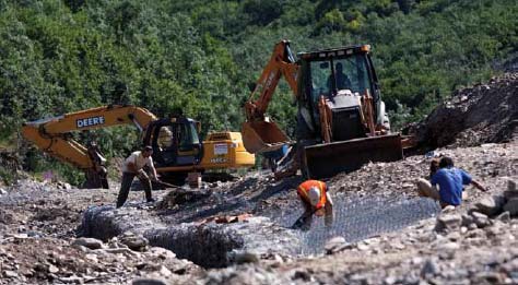 people and construction equipment working in a rocky stream bed people and construction equipment working in a rocky stream bed