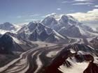 aerial view of a vast white mountain with numerous glaciers and smaller mountains