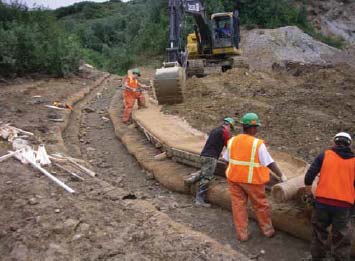 four men constructing a stream embankment