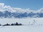 snowy mountains behind a vast snowy field with people in it