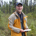 man in a yellow jacket in a spruce forest
