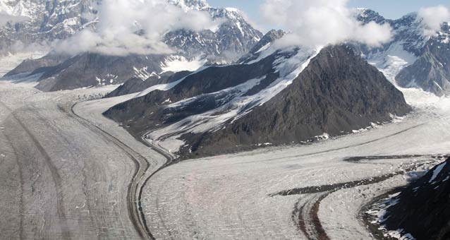 vast glacier split in half by steep, snowy mountains