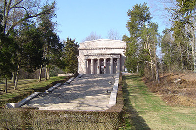 Broad stairs ascend up the slope toward the memorial, stone with a line of columns across the front.