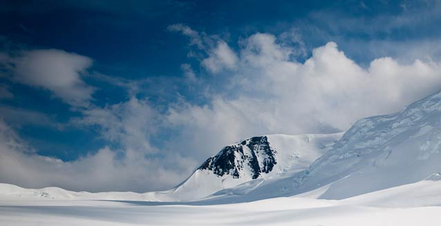 snowy mountains with puffy clouds overhead snowy mountains with puffy clouds overhead