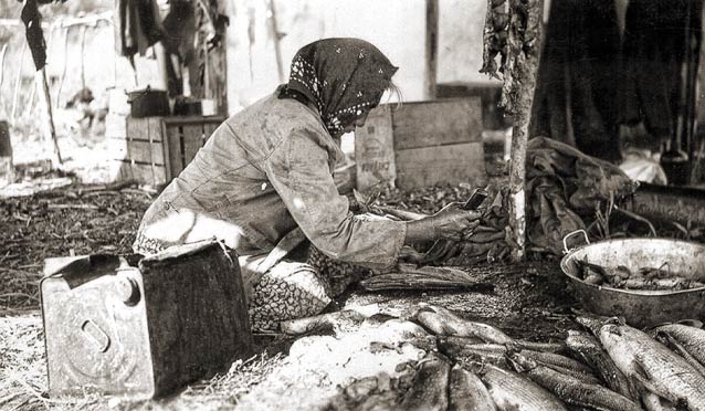 a woman kneeling over a pile of fish