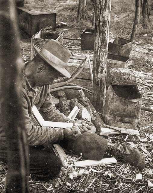 man kneeling amid wood shavings, fitting pieces of wood together man kneeling amid wood shavings, fitting pieces of wood together