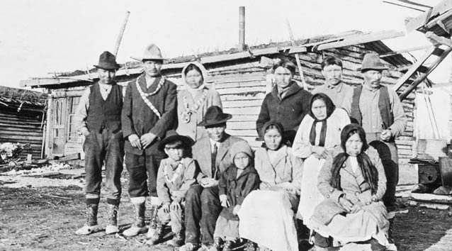 10 adults and two small children in front of a wood framed building