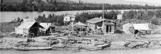 log cabin and other wood structures near a river