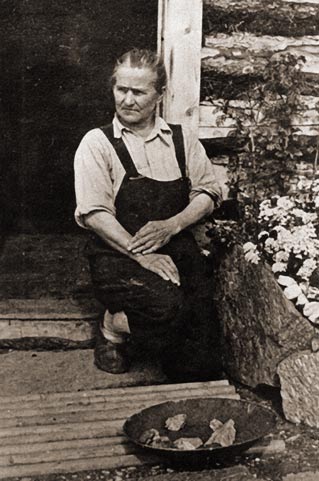 black and white historic image of a woman kneelilng by a pan full of gold nuggets black and white historic image of a woman kneelilng by a pan full of gold nuggets