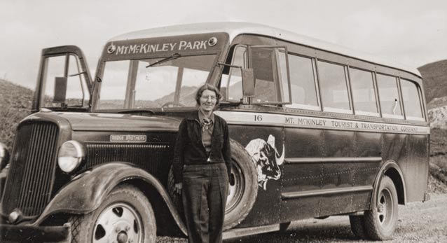 black and white historic image of woman standing near a bus black and white historic image of woman standing near a bus
