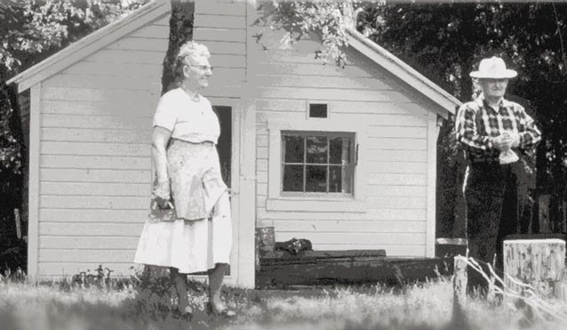 black and white image an elderly man and woman near a white colored house 