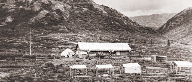 historic image of log cabin and small enclosures at the foot of a large hill historic image of log cabin and small enclosures at the foot of a large hill
