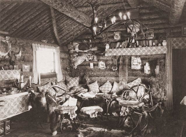 interior of a log cabin filled with pillows & furniture made from caribou antlers