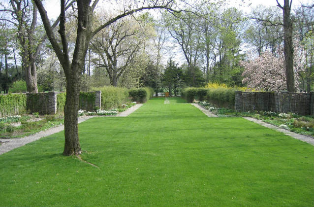 An expanse of manicured green lawn flows through the center of the formal gardens.