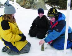 three kids kneeling in the snow