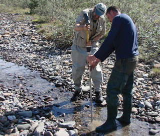 two people putting a pipe into the ground