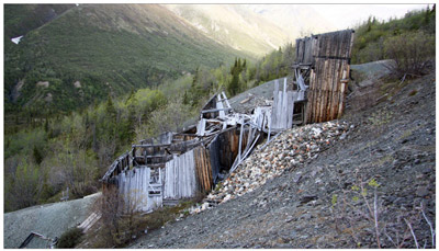 A timber-framed structure, built on a hillside, is missing a roof. 