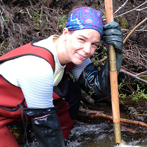 Woman kneels in stream with a net