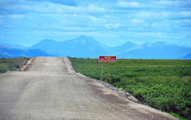 dirt road leading across a tree-less plain toward distant mountains dirt road leading across a tree-less plain toward distant mountains