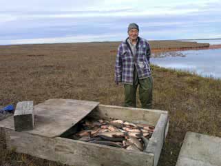 man standing next to a box with fish in it