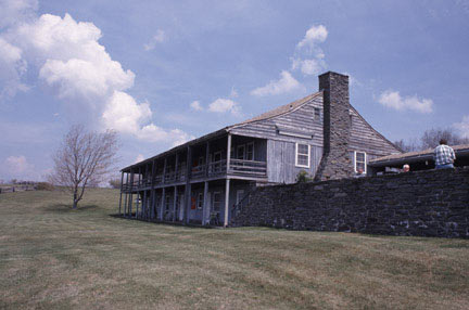 A stone and wood lodge has porches on the ground level and the floor above.