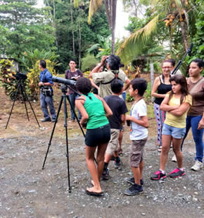 A group of children in Costa Rica line up to look through a bird spotting scope.