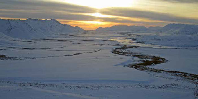 sunset over a snowy valley and snowy mountains