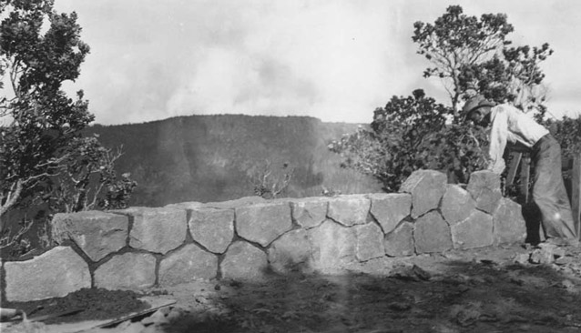 A man leans to look over a carefully-laid, mortared stone guard wall. A man leans to look over a carefully-laid, mortared stone guard wall.