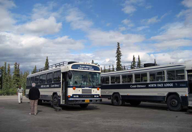 two buses in a gravel parking lot two buses in a gravel parking lot