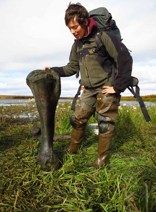 woman standing next to a large fossil