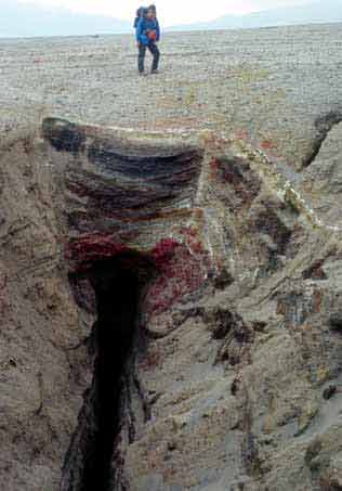 person standing next to a rocky chasm person standing next to a rocky chasm