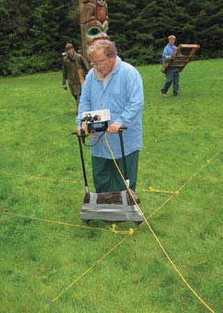 man standing in a field near a totem pole