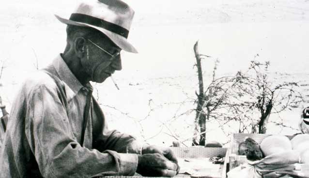 man sitting at a table outside smoking a cigarette